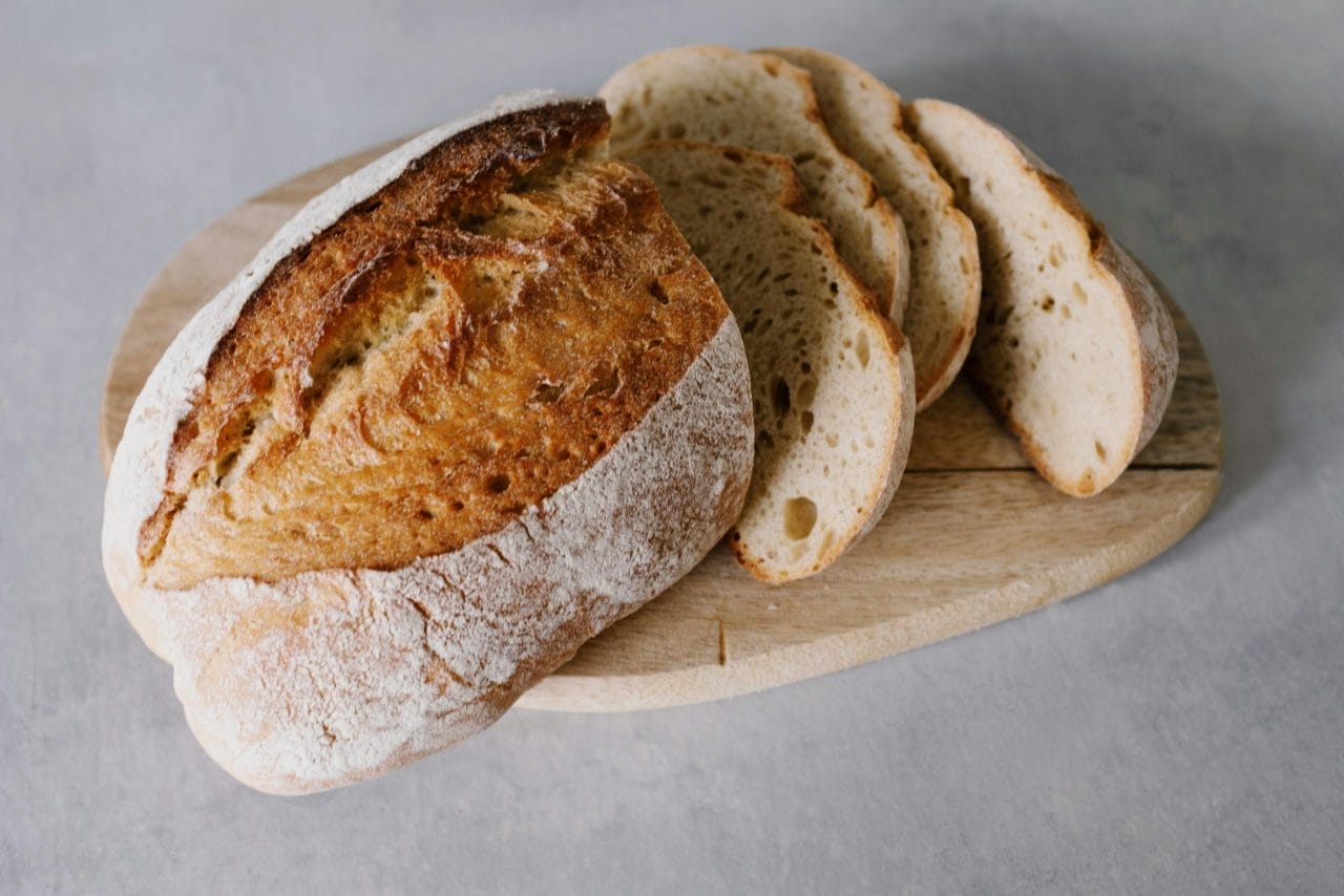Sliced sourdough bread on a wooden board showcasing its texture and freshness.