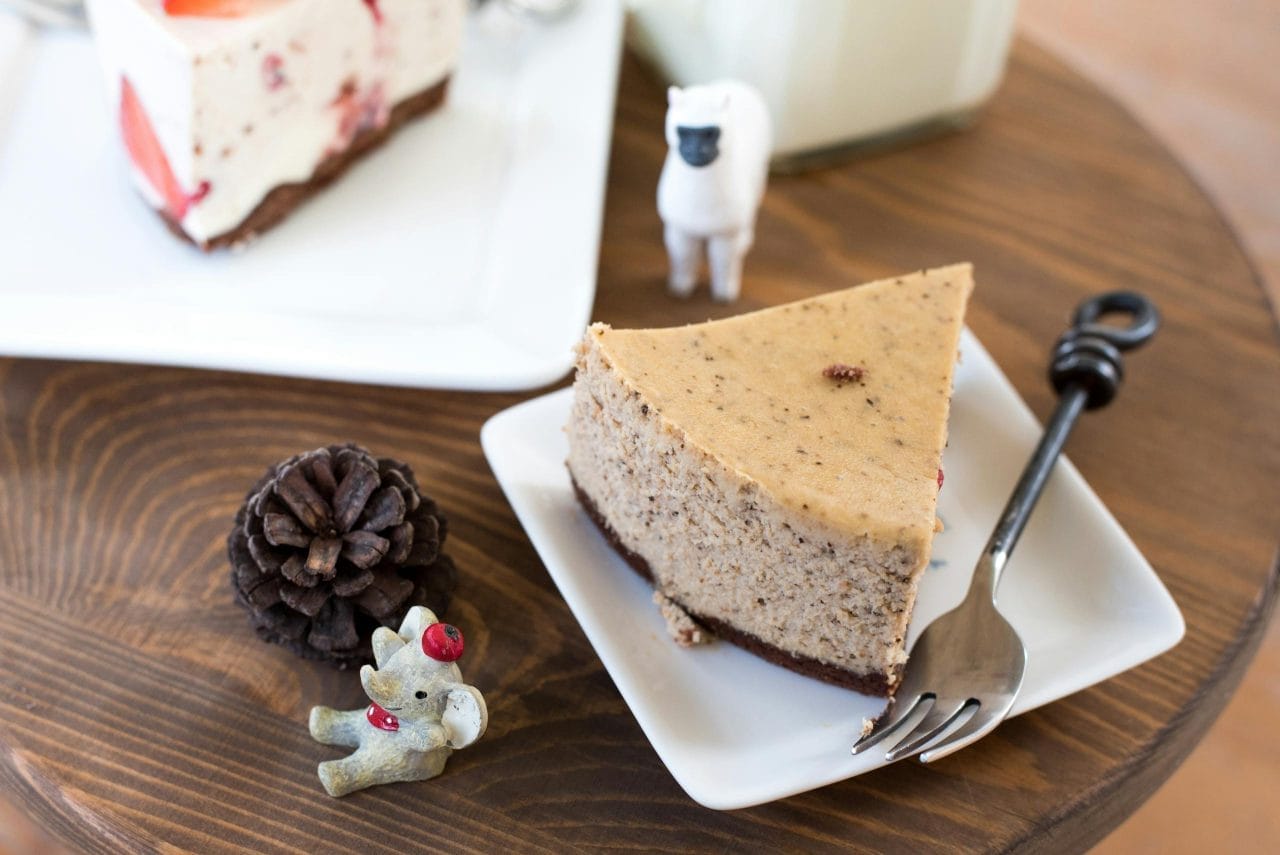 Top view of a cheesecake slice with figurines on a wooden table, perfect for dessert lovers.