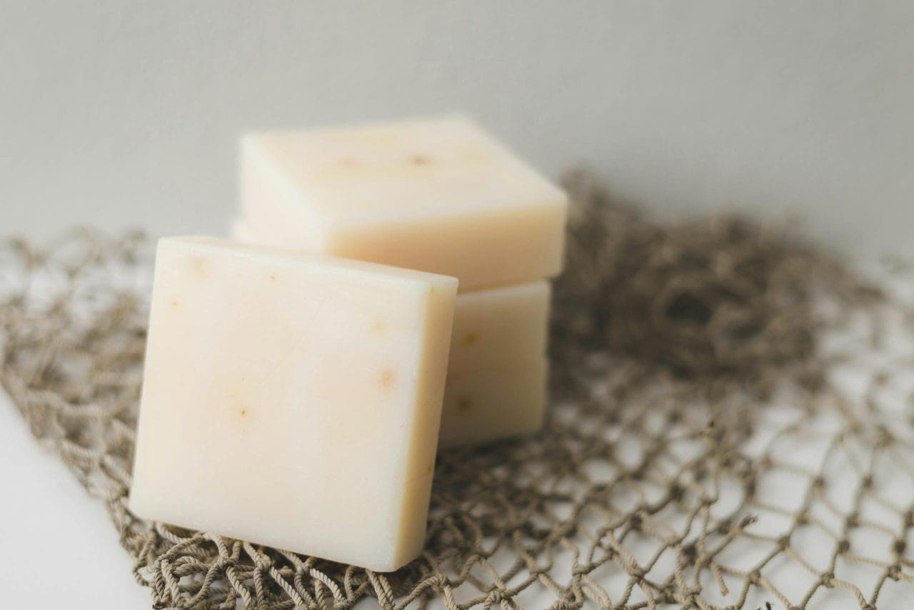 Close-up of creamy cheese blocks stacked on netting, perfect for food photography.